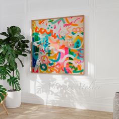 a painting hanging on the wall next to a potted plant in a white room