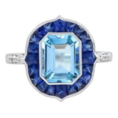 This creation is exquisite. At the heart of this ring is a stunning emerald cut blue topaz, framed by the most delicate milgrain textures. The center blue topaz is accented by French cut blue sapphires. This is a perfect piece for an engagement or a statement ring. Ring Information Style: Art-deco Metal: 18K White Gold Total weight: 4.70 g. (approx. total weight) Center Gemstone Type: Blue Topaz Shape: Emerald Cut Size: 9 x 7 mm. Number: 1 Weight: 2.95 Carat (approx.) Accent Gemstones I Type: Sapphire Shape: French Cut Size: 3 - 4 mm. Number: 20 Weight: 3.46 Carat (approx.) Shoulder Gemstones Type: Diamond Shape: Round Average Color: H Average Clarity: SI Size: 1.3 mm. Number: 6 Weight: 0.06 Carat (approx.) This ring will be made to your order in 1-2 weeks, contact us to find out more. An Diamond Ring With Halo, Ring With Halo, Engagement Ring On Hand, Estate Diamond Jewelry, Diamond Sapphire Engagement Ring, Sapphire Diamond Engagement, Bracelet Love, French Cut, Aquamarine Engagement Ring