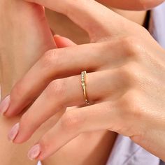 a woman's hand wearing a gold ring with two diamonds on the middle finger