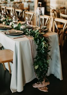 the table is set with greenery and place settings