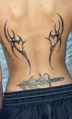 the back of a man with tattoos on his body and an arrow tattoo design on his lower back