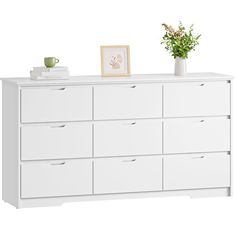 a white dresser with drawers and flowers on top