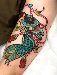 a person with a tattoo on their arm and leg, holding a rope in the shape of a fish