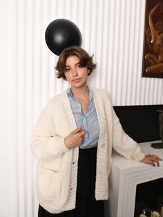 a woman standing next to a table with a black balloon on top of her head