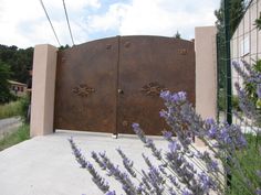 an iron gate with purple flowers in front of it