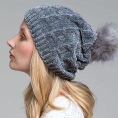 a woman wearing a gray hat with a fur pom - pom on it