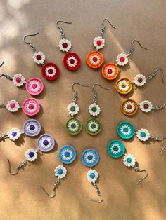 a bunch of earrings that are sitting on a table together, all in different colors