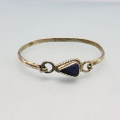 I love the work of the Mexican Silversmiths of the past. This simple bracelet is beautifully made with sterling silver and blue Lapis Lazuli. The bracelet is slightly out of being a perfect oval but it fits well on my 7 1/4 inch wrist as there is a bit of give. The bracelet measures 2 1/2 inches side to side and 2 inches front to back. The front measures 5/8th inches high. It is marked, 925 for Sterling, Mexico and part of a maker's mark, TC. This will be mailed in a lovely gift box. If you like Vintage Lapis Lazuli Jewelry, Spiritual Bangle With Sterling Silver Clasp, Vintage Sterling Silver Everyday Bracelets, Vintage Sterling Silver Bracelets For Everyday, Vintage Sterling Silver Everyday Bracelet, Adjustable Sterling Silver Bangle, Sterling Silver Gemstone Bangle, Stackable Sterling Silver Bracelet For Anniversary, Sterling Silver Hallmarked Bangle Bracelet