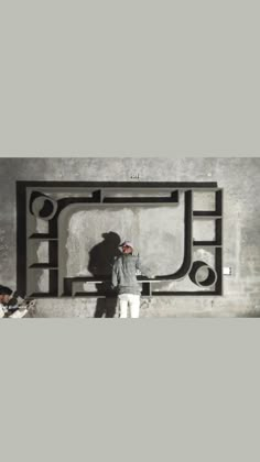 a man standing in front of a wall with a large metal object on it's side