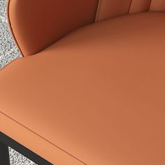 an orange chair sitting on top of a cement floor next to a black metal table