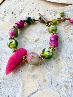 Large hot pink agate centre piece stone, set with venetian glass beads, pink-green agate stones, handprinted African hot pink bone beads, Vintage Indian gold spacer beads, finished of with a vintage African brass loop clasp. Stone and glass trinkets on the end. Adjustable Artisan Pink Beaded Bracelets, Pink Bohemian Jewelry With Faceted Beads, Bohemian Pink Jewelry With Faceted Beads, Pink Artisan Beaded Jewelry, Pink Beaded Czech Glass Jewelry, Artisan Pink Jewelry With Round Beads, Pink Glass Jewelry With Colorful Beads, Pink Glass Jewelry With Faceted Beads, Bohemian Pink Jewelry With Gemstone Beads