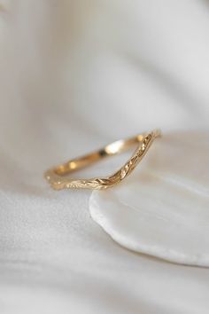 a close up view of a gold ring on a white cloth with a flower in the background