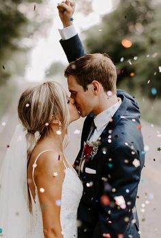 a bride and groom kissing in front of confetti