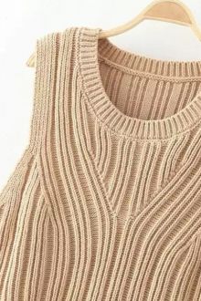 a beige sweater hanging on a hanger with the top half turned to show it's ribbing