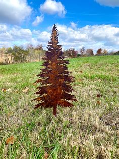 a small metal tree sitting in the middle of a field