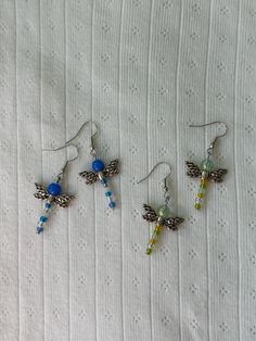 three pairs of earrings with dragon charms on them sitting on a white cloth covered surface