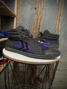 a pair of shoes sitting on top of a metal stool next to a rope rack