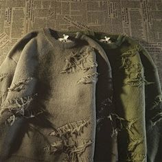 two sweaters with holes on them sitting on a table