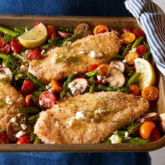 a pan filled with chicken, asparagus, tomatoes and other veggies