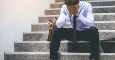 a man sitting on steps with his hands to his face