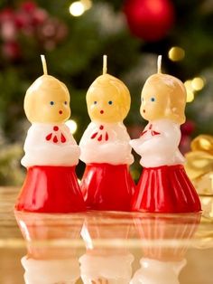 three small candles are sitting in front of a christmas tree