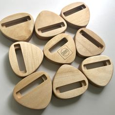 six wooden cutting boards with holes cut in half on a white surface, one has a black handle and the other is made from wood