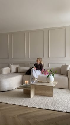 a woman sitting on top of a couch in a living room next to a coffee table