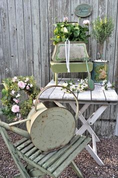 an old chair and table with flowers on it in front of a wooden fenced area