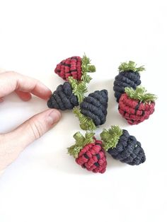 a hand is holding four small knitted strawberries