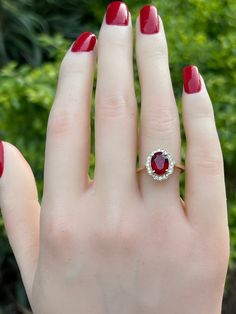 a woman's hand with red nails and a ring on it