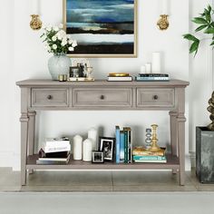 a console table with books and vases on it