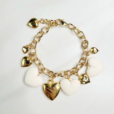 Vintage hearts are the focal point of this love filled bracelet. An assortment of gold plated hearts and matte ivory hearts play along the edge, perfect as a gift for someone you love. Handmade in the United States, a matching necklace and earring set are available. Features: - Gold Plated Vintage Hearts - Matte Ivory Vintage Hearts - Gold Plated Mixed Cable Chain - Lobster Claw Clasp - Extension - Handmade in the United States Dimensions: - Length: 7.5" - Extension: 1" - Total Length: 8.5" Heart-shaped Jewelry With Dangling Charms For Valentine's Day, Heart-shaped Dangling Charms Jewelry For Valentine's Day, Dainty White Heart Bracelet For Anniversary, White Heart Charm Bracelet For Anniversary, Gold Metal Charm Bracelet With Heart Beads, Elegant White Heart Bracelet For Valentine's Day, White Heart-shaped Metal Charm Bracelet, Elegant White Heart Charm Bracelet, Elegant White Charm Bracelet With Heart Charm