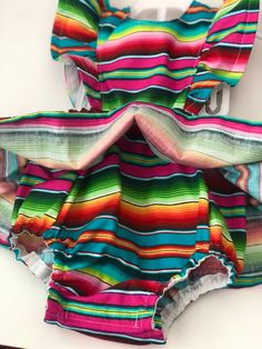 Perfect for all the summer 🥳 FIESTAS!! Handmade skirt romper. Made with cotton serape cotton fabric. These amazing pieces are made to order. Sizes 0-6 month up to 4T are made with attached bloomers and snaps at the saddle. Anything above a 4t (5t -7/8y) are the same style dress with no bloomers attached. If you have any questions on sizing please don't hesitate to message me. I will gladly help. Rainbow Summer Dress For Playtime, Rainbow Summer Dresses For Playtime, Summer Rainbow Playtime Dress, Fun Multicolor Sundress For Playtime, Playful Rainbow Cotton Dresses, Multicolor Summer Sundress For Playtime, Rainbow Cotton Dress For Playtime, Rainbow Cotton Playtime Dress, Playful Beach Dress With Colorful Pattern