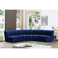 a large blue sectional sofa sitting in a living room next to a table and window