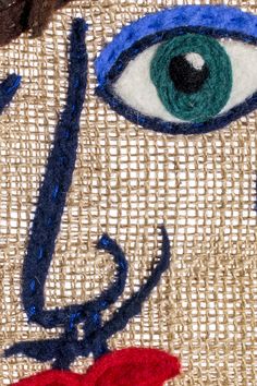 a close up view of an eye on a piece of burlied fabric with blue and red thread