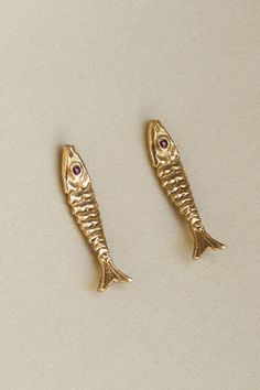 The detail in our Pisces earrings bring the ocean to its wearer, honoring the relation between sea and land by offering a portrait in earth's precious metals and stones. This fish is unique in its aversion to water. Please remove your Pisces Studs before bathing or taking a dip to protect the stone's setting. Gold vermeil or solid 14k fish with precious stone eyes. 1" in length. Sold as a single earring or a pair. The 14k Pisces studs are paired with solid 14k gold earnuts. Rubies speak to our i Gold Fish Earrings, Fish Earing, Colorful Piercings, Timeless Jewelry Pieces, Sardine Earrings, Piercing Ideas Unique, Ear Scape, Pisces Earrings, Sea Jewellery