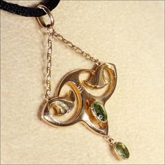 "This gorgeous Art Nouveau pedant has a touch of Egyptian revival flare. With it's floral motifs and bright sparkling spring green Peridot gems, this lovely piece has wonderful lines that make me long for warm days in the garden. This hand crafted pendant was made in England in about 1900. The two peridots add up to about .65 carats. The pendant measures 46.2 mm across and 32.2 mm top to bottom (26.8 mm not including the chain), it weighs 1.6 grams. Thanks! If you like this piece and would like Art Nouveau Historical Jewelry For Formal Occasions, Art Nouveau Jewelry With Historical Design For Formal Occasions, Art Nouveau Jewelry With Historical Design For Formal Events, Art Nouveau Yellow Gold Jewelry With 17 Jewels, Art Nouveau Yellow Gold Jewelry For Formal Occasions, Antique May Birthstone Jewelry For Formal Occasions, Art Nouveau Pendant Jewelry For Formal Occasions, Collectible Art Nouveau Yellow Gold Jewelry, Art Nouveau 14k Gold Jewelry For Anniversary