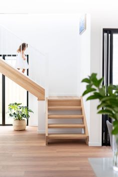 a woman is walking up the stairs in her home with plants on the floor and potted plant