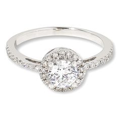 a white gold ring with diamonds on the band and a round center stone in the middle