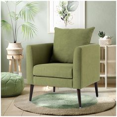 a green chair sitting on top of a rug in a living room next to a potted plant