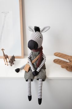 a stuffed zebra sitting on top of a white shelf