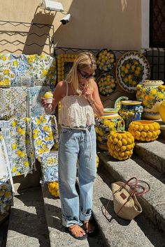 a woman standing in front of a display of lemons and other yellow items on steps