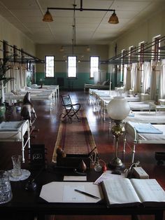 an empty room filled with lots of white furniture and books on top of a wooden floor