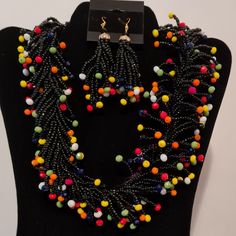 multicolored beaded necklace and earring set on black mannequins