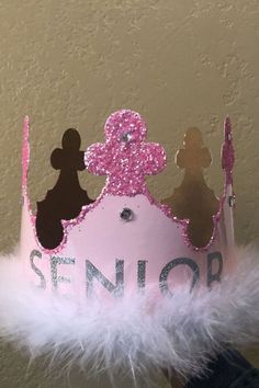 a pink princess crown with the word senior on it and two silhouettes painted on it