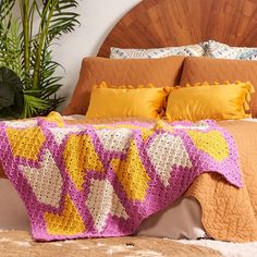 a crocheted blanket is draped over a bed with pillows and blankets on it