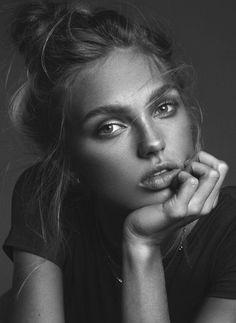 a black and white photo of a woman with her hand on her chin looking at the camera