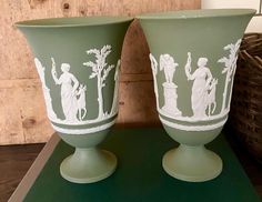 two green vases with white designs on them