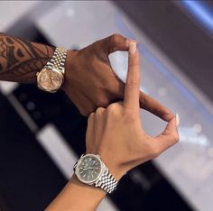 two hands holding onto each other with wrist watches on their wrists and one hand in the air