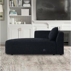 a black couch sitting in front of a tv on top of a white book shelf